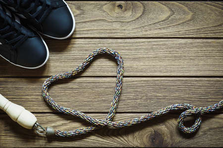 Healthy lifestyle love concept - Top view of sport shoes and jump rope in heart shape on wooden  backgroundの写真素材