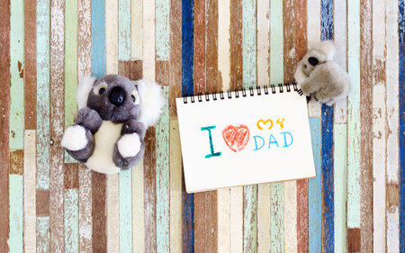 Fathers day greeting card concepts with I love my Dad text and cute koala dolls. Top view on wooden background.の写真素材