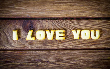 I love you. Text from the salty crackers as printed English letters that lie on a wooden background. Top view.の写真素材