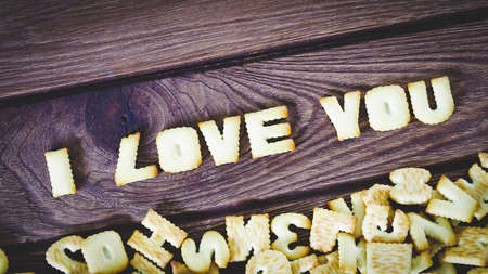 I love you. Text from the salty crackers as printed English letters that lie on a wooden background. Top view.の写真素材