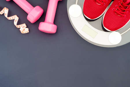 Fitness and weight loss concept, running shoes, dumbbells, tape measure, weighting scale, top view with copy spaceの写真素材