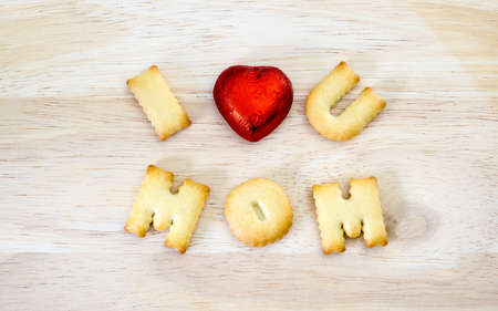 Mother's day Greeting card concept. I love you mom. Text from the salty crackers as printed English letters that lie on a wooden background. Top view.の写真素材