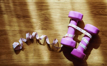 dumbbell and measuring tape  on wooden background,Sport equipment,Healthy lifestyle concept,Top view with copy spaceの写真素材