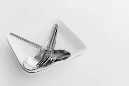 Empty plates with spoon and fork on a white table with copy space, selective focusの写真素材