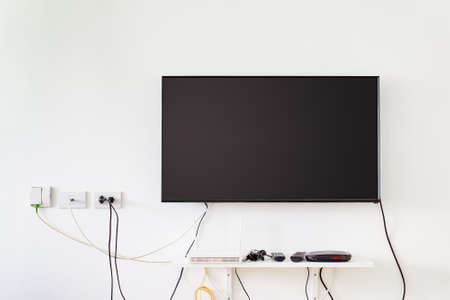 lcd tv on wall with remote, wireless internet access point and set top boxの写真素材