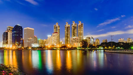 Bangkok, Thailand- June 3, 2017: Bangkok city skyline and office buildings in twilight time with skyscrapers and lights reflecting in the lake at Benjakitti Public Park, Bangkok, Thailand.の写真素材