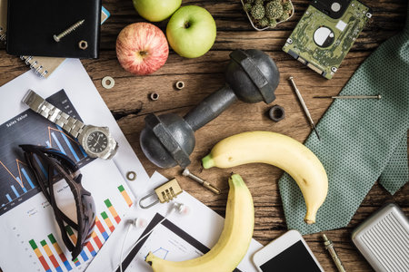 Healthy Business Active lifestyles concept. healthy fruits and active lifestyles, dumbbells, apples, neckties, smartphone, business graph sheets on wood background. Top view.の写真素材