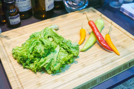 Red chilli pepper with lettuce on a wooden Chopping Board for Thai food preparingの写真素材