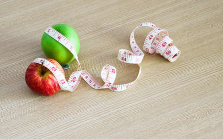 Top view of fresh red apple and green apple with measuring tape on wood table background with copy space for your text, Healthy fruit for healthy life and dieting conceptの写真素材