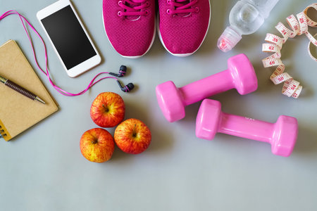Fitness, healthy and active lifestyles Concept, dumbbells, smart phone, sport shoes, tape measure, bottle of water, notebook on wood background. top view with blank copy spaceの写真素材