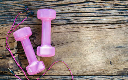 Fitness, healthy and active lifestyles Concept, pink dumbbells and earphones on wood background. top view with blank copy spaceの写真素材