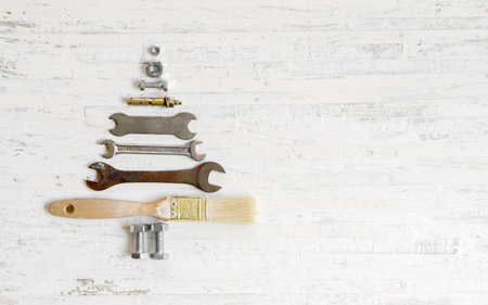 Paint brush wrench, nuts and bolts decorated as christmas tree on a white wooden background....