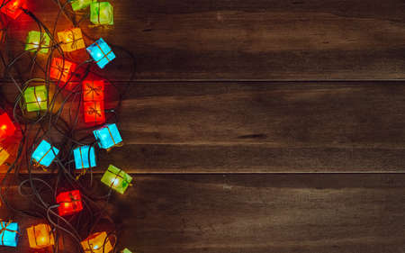 Christmas lights background. Merry christmas (xmas) and Happy new year background. Glowing colorful Christmas lights gift boxes on wood texture background vintage tone. Top view with free space for your textの写真素材