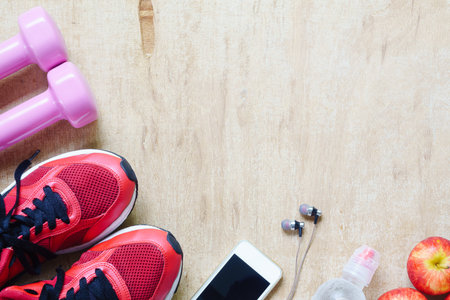 Fitness, healthy and active lifestyles Concept, dumbbells, smart phone, sport shoes, bottle of water on wood background. top view with blank copy spaceの写真素材