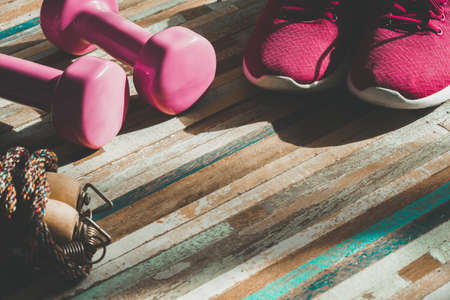Fitness, healthy and active lifestyles concept, Still life of dumbbells, sport shoes, and jump rope  on wood background vintage tone with copy spaceの写真素材