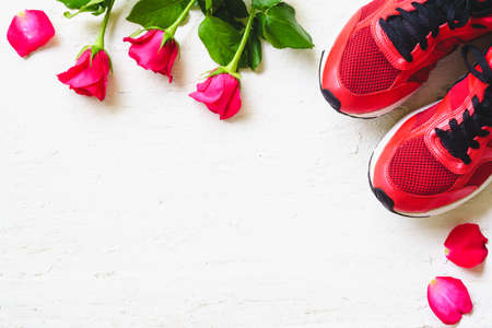 Red sport shoes  and red roses on white wooden background, Valentines sports background and greeting card for any anniversary holiday background concept top view with copy space.の写真素材