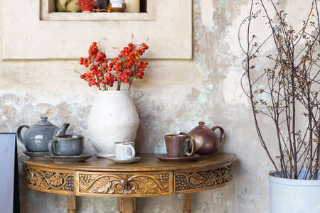 Still life details, cup of tea and cup of coffee on outdoor retro vintage wooden coffee table shelf decorated with red flowers and dry flowers .の写真素材