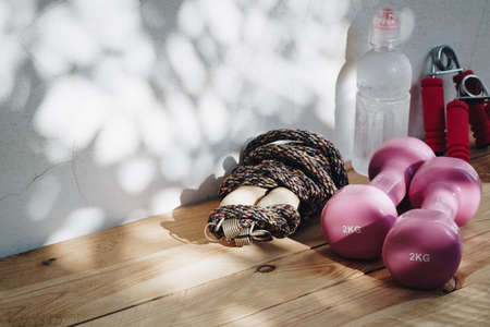 Healthy and active lifestyles Concept, Still life shot of dumbbells , jump rope, exercise equipments and bottle of water on wooden plank background with copy spaceの写真素材