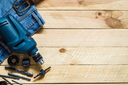 blue electric power drill with set of bit and blue jeans on gruge wooden  plank background top view with copy spaceの写真素材