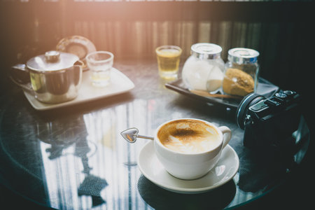 Coffee and tea time relaxing time from travel concept. Cup of Coffee , tea, camera and teapot on table in a coffee shop.の写真素材