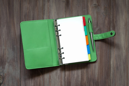 Open blank green organizer book on wood background top view with blank space for your text