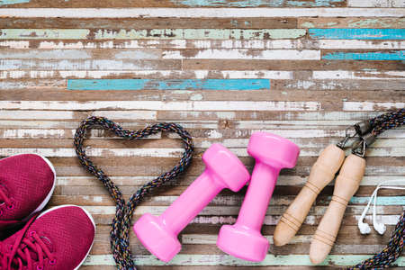 Weight and Dieting Fit and Beauty Healthy lifestyle concept. Sport equipment, Dumbbells, running shoes, skipping ropes on wooden background.の写真素材