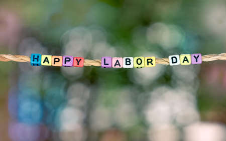 Happy Labor Day word hanging by rope with beautiful green nature colorful bokeh backgroundの写真素材