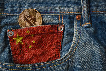 Golden BITCOIN (BTC) cryptocurrency in the pocket of jeans with the flag of Chinaの写真素材