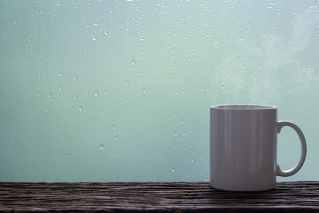 Steaming coffee cup on a rainy day window background