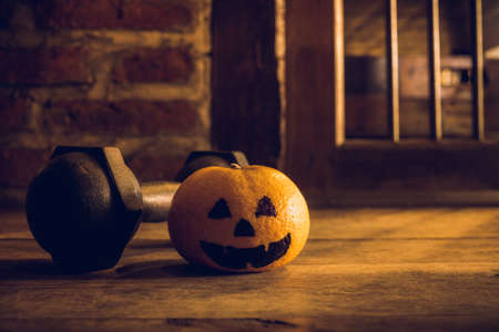 Orange with Head Pumpkins  haunted spooky face  with black iron dumbbell. Halloween Festival with Fitness, Exercise, Working out, weight and dieting, healthy lifestyle background concept.の写真素材