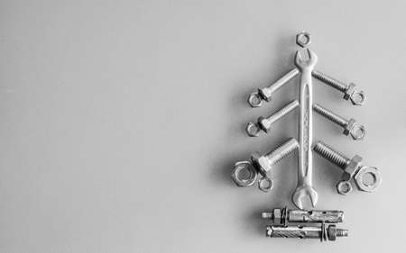 Wrench, nuts and bolts decorated as Christmas tree on a gray background. Christmas greeting card and Happy new year greeting card concept. Top view with copy space for your textの写真素材