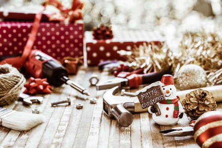 Merry Christmas and Happy New Years Handy Constrcution Tools background concept.  Handy House Fix DIY handy tools with Christmas ornament decoration on a rustic wooden table.の写真素材