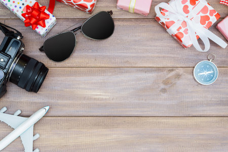 Top view of gift boxes, camera, sunglasses, and plane model on wood. Valentines travel holiday, Honey moon trip, summer holiday vacation conceptの写真素材