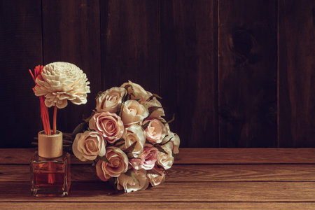 Aromatic reed freshener, Fragrance Diffuser Set of bottle with aroma sticks (reed diffusers) with rose flower on wood background. Romantic background tone for Valentine's day background concept.の写真素材