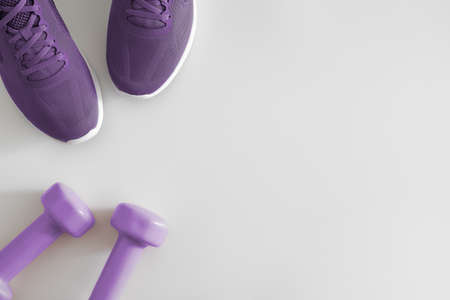 Flat lay top view Fitness accessories on a White background. Purple dumbbells and purple sport shoes on white with copy space. Healthy lifestyle concept.の写真素材