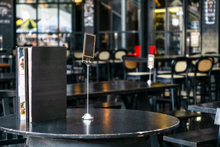 Mock up blank cover menu frame on the blurred background of  outdoor coffee and restaurant terrace...