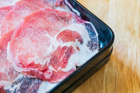 Top view of fresh thin pork slices for Shabu, Sukiyaki, hot pot or grill on barbecue brass pan.の写真素材