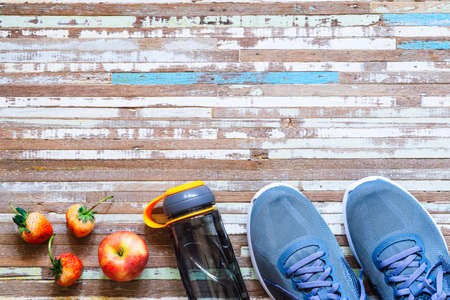 Apple, Strawberries, bottle of water and running shoes on rusty wood background. Active healthy lifestyle concept background.の写真素材
