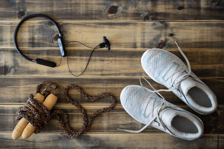 Fitness and healthy active lifestyle love background concept.  Training sneakers,  jump rope with heart shape, and headphones on wooden backdrop. Flat lay top view.の写真素材