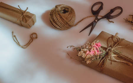 Still life shot of Beautiful small handmade DIY gift box (package) with flowers and decorative rope on white background.の写真素材