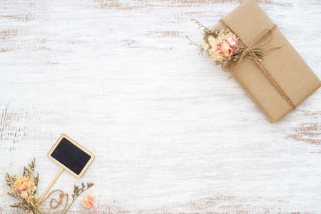 Beautiful small handmade DIY gift box (package) with flowers and decorative rope on rusty white background. Vintage Retro Style. Flat lay Top view with copy space for your advertisement text.の写真素材
