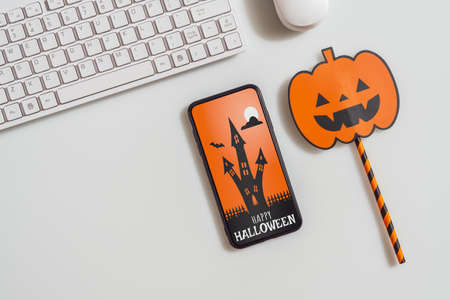 Happy Halloween Mobile phone mockup background concept. Top view of smartphone on office desk table with accessories. Flat lay design. Business and technology Halloween day concepts ideas.の写真素材