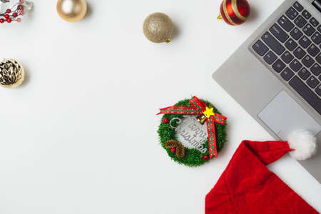 Flat lay top view Christmas office table desk party concept, Christmas workspace with laptop, Santa Claus hat and Christmas decorations on white backgroundの写真素材