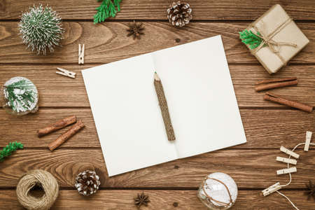 Top view of blank notebook on wood  background with xmas decorations. Mockup Christmas background with notebook for wish list or to do list. Flat lay with copy space.の写真素材