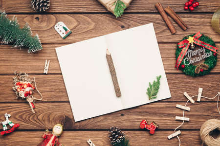 Top view of blank notebook on wood  background with xmas decorations. Mockup Christmas background with notebook for wish list or to do list. Flat lay with copy space.の写真素材