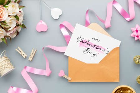 Mockup postcard and envelope on grey background with Happy valentines day, handy craft, gift box bow and pen. Mock up for elegant design. Flat lay top view valentine's day background.の写真素材