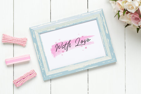 Mockup photo frame for Valentines day concept. Top view of mock up photo frame with craft decoration and rose flowers on white wood background.の写真素材