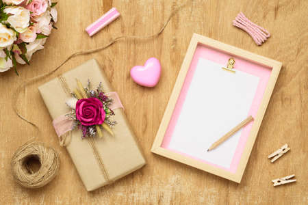Mockup Blank photo frame for Valentines day concept. Top view of mock up photo frame with beautiful craft gift box decoration and rose flowers on grunge wood background.の写真素材