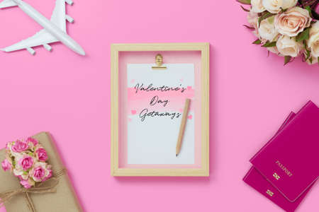 Mockup picture frame for travel with valentines day & love season background concept. Top view of mock up photo frame with craft gift box, passport, sea shell, airplane model on pink background.の写真素材