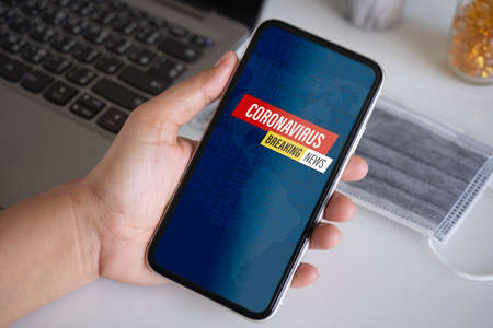 A person holding smartphone with Coronavirus breaking news message on the cellphone.の写真素材